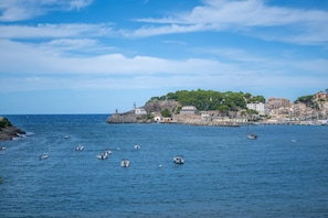 Une ville côtière avec un phare, des bateaux et des bâtiments qui bordent la côte.