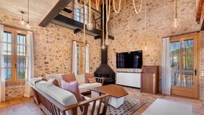 A stone-walled living room with a fireplace, sofa, and coffee table. - Holiday Home 'Masia Can Divi' with Mountain Views, Wi-Fi and Air Conditioning (Ametlla del Valles)
