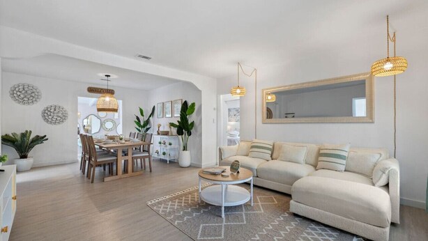 A modern living room with a sofa, dining table, and chairs, a round coffee table, and decorative wall art.
