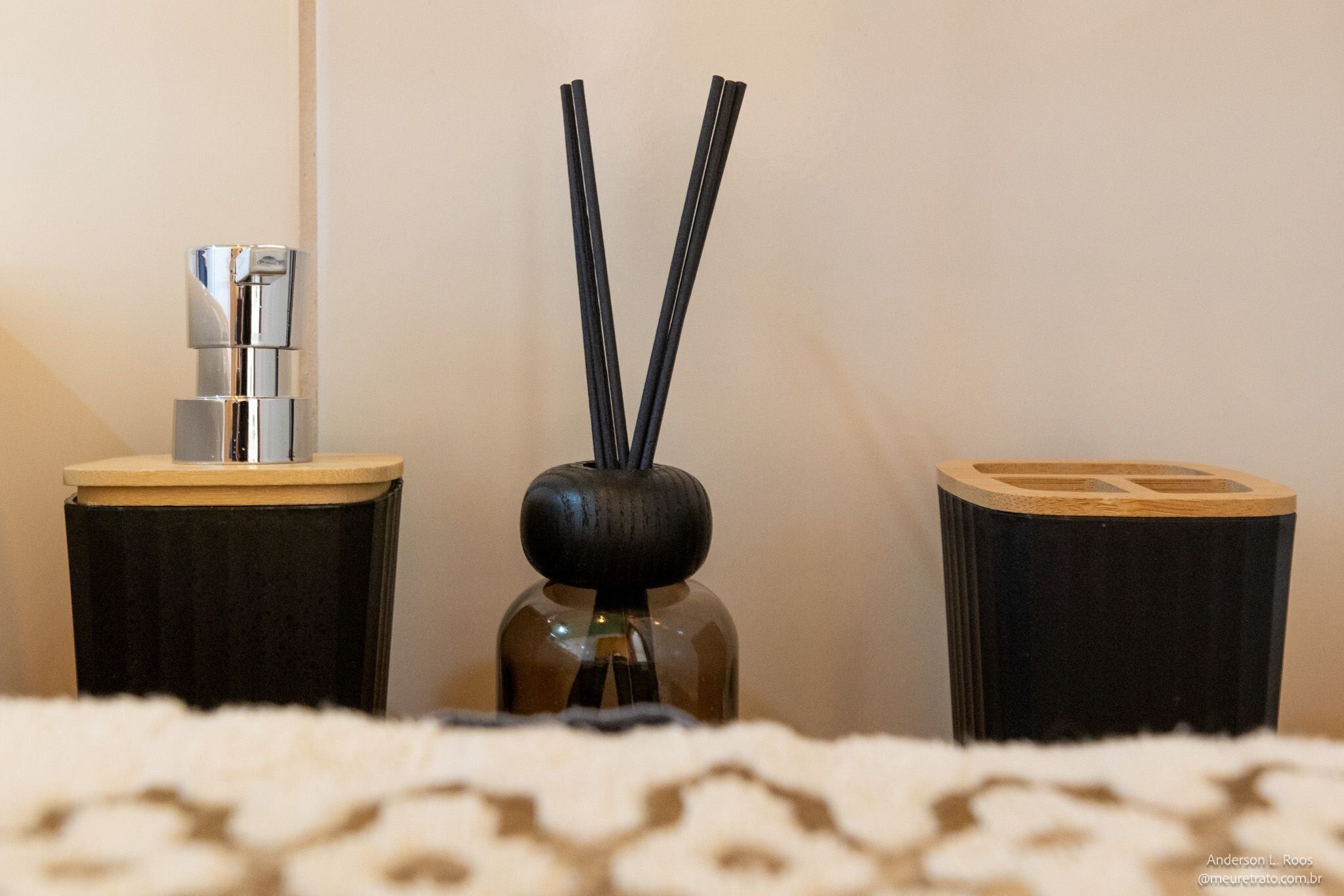 A room with a small table, a bottle with black sticks, and a metallic object on a wooden base.