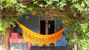 Una hamaca atada entre árboles, un banco de madera y una puerta con un adorno circular.