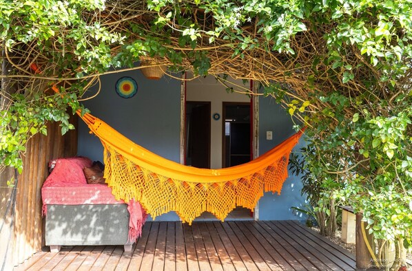 A hammock tied between trees, a wooden bench, and a door with a circular decoration.