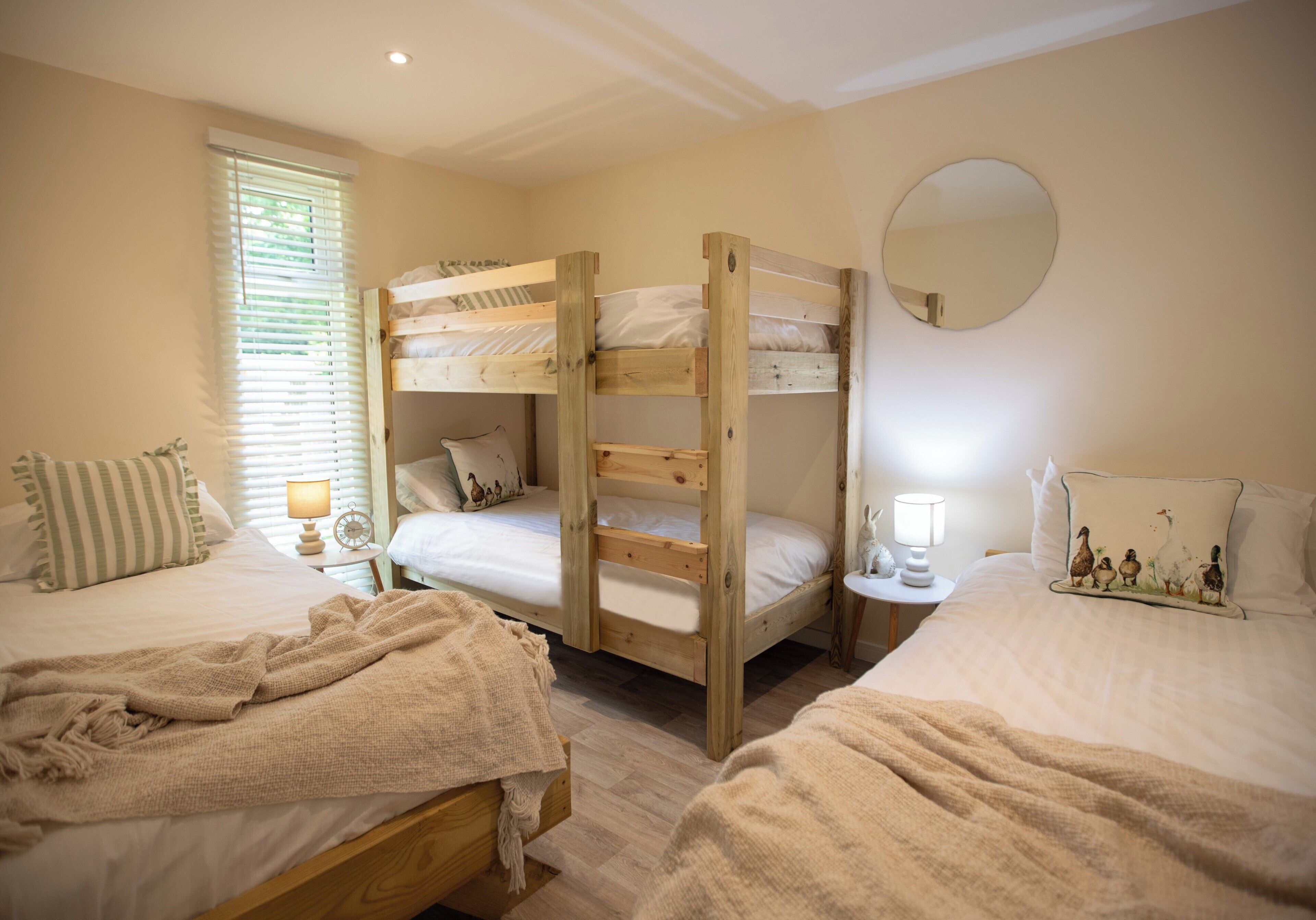 Une chambre avec deux lits superposés, un miroir rond et une table de chevet avec une lampe.