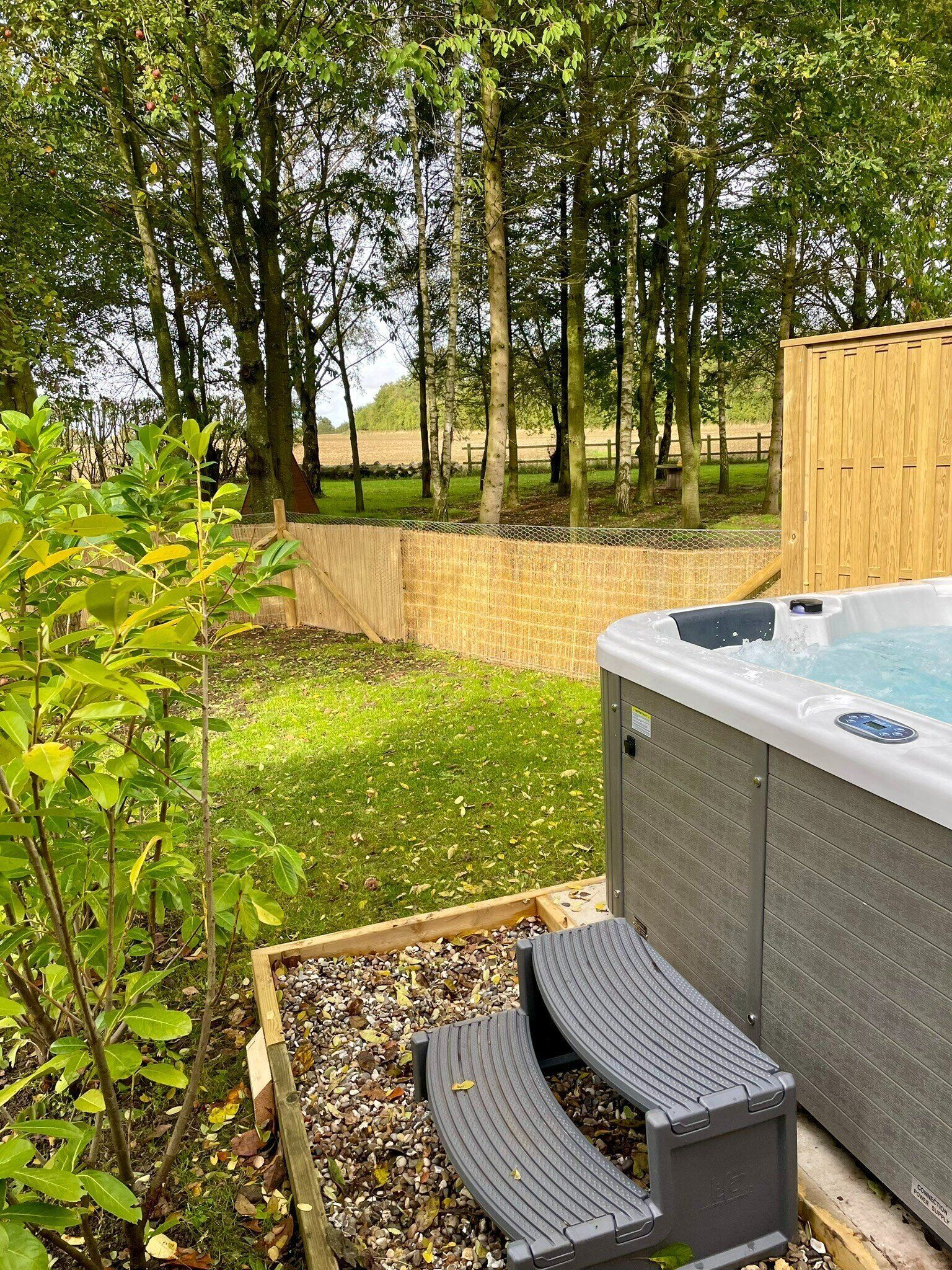 Un bain à remous dans un jardin, avec une terrasse en bois et une pelouse.