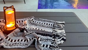 A poolside area with lounge chairs, a pool, and a candle on a table.
