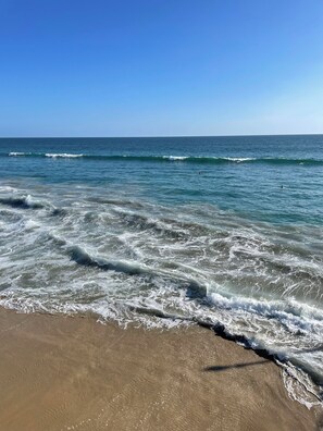 A beach with waves crashing onto the shore and a clear blue sky. - Poolside Bliss in Gulfport: Stylish 3BR Beachy Retreat Awaits (Gulfport)