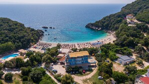 Une vue aérienne d’une zone côtière avec une plage, une piscine et plusieurs bâtiments.