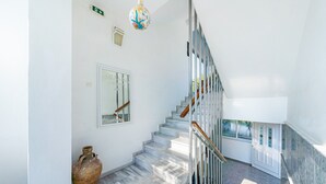 Un escalier avec un mur blanc, un grand vase et un luminaire en forme de globe.
