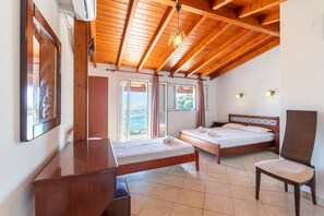 Une chambre avec deux lits, un bureau, une chaise et une vue sur la mer.
