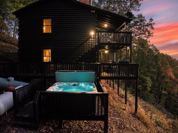 Eine Hütte mit Whirlpool, Sitzgelegenheit im Freien und einer Treppe, die zu einem Balkon führt.