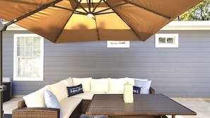 A covered outdoor seating area with a sofa, a coffee table, and an umbrella. - Cozy Oasis in San Marcos TX, Modern, Pet Friendly, convenient Location, Sleeps 8 (San Marcos)