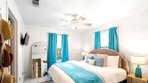 A bedroom with a bed, a ceiling fan, a nightstand, a lamp, and a window with curtains. - Cozy Oasis in San Marcos TX, Modern, Pet Friendly, convenient Location, Sleeps 8 (San Marcos)