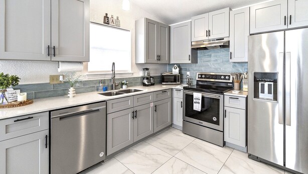 A modern kitchen with stainless steel appliances, grey cabinetry, and a tiled backsplash. - Cozy Oasis in San Marcos TX, Modern, Pet Friendly, convenient Location, Sleeps 8 (San Marcos)