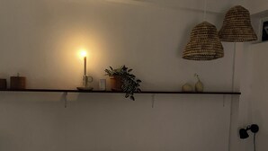 Een slaapkamer met een bed, een plank met decoratieve objecten en een hanglamp.