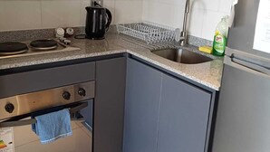 Eine kleine Küche mit Herd, Backofen, Spüle und Kühlschrank.