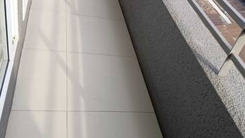 A balcony with a tiled floor and a metal railing.