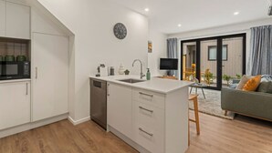 A modern kitchen with white cabinetry, a built-in dishwasher, and a central island with a sink.