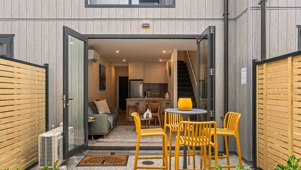 A modern apartment with a kitchen, dining area, and a staircase leading to an upper floor.