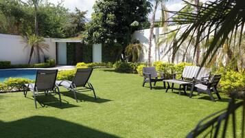 A patio with artificial grass, outdoor furniture, and a pool.