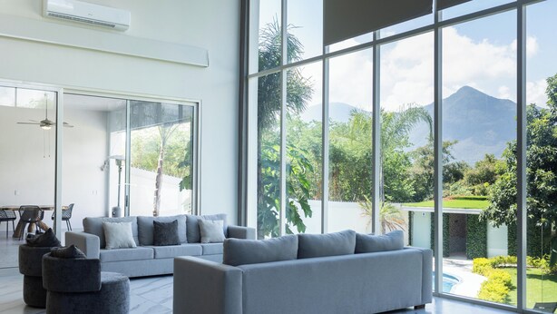 A spacious living room with a large grey sectional sofa, a small grey ottoman, and a dining area with a table and chairs. - Luxurious Getaway w Private Pool Garden (Santiago)