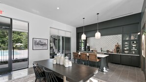 Een moderne keuken met een groot eiland, donkere kastjes en hanglampen.