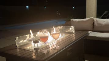 A glass table with two glasses of wine and a candle.