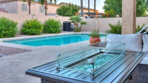 Un bar junto a la piscina con cerramiento de cristal, una tumbona y una planta en maceta.