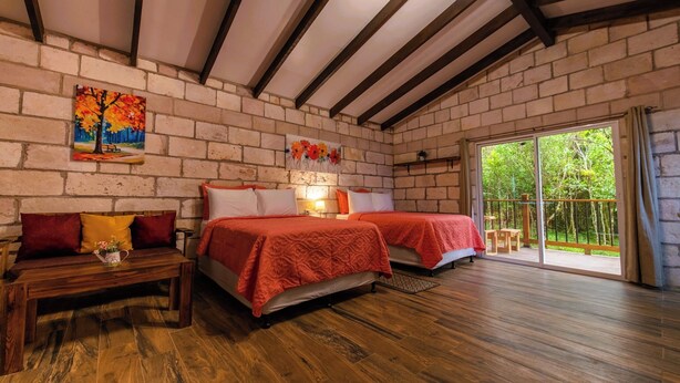 Una habitación con dos camas, un banco de madera y un cuadro en la pared.