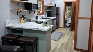 A modern kitchen with a central island, wooden shelves, and a built-in oven. - Charming cabin in outside lovely coombs  on 10 acreas  veryprivate  (Qualicum Beach)