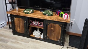 A wooden entertainment center with a flat-screen TV, a small Christmas tree, and a 'NOEL' sign. - Charming cabin in outside lovely coombs  on 10 acreas  veryprivate  (Qualicum Beach)