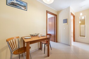 Ein Essbereich mit Holztisch und -stühlen, einem gerahmten Bild an der Wand und einer Tür zu einem anderen Raum.