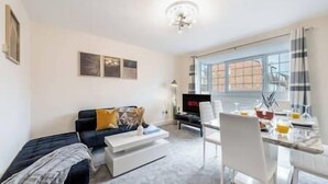 A modern living room with a sofa, coffee table, and dining area with chairs and a table.