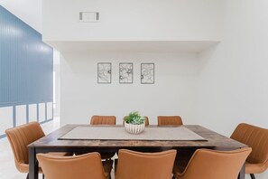 A conference room with a long table, six chairs, a plant centerpiece, and three framed floral artworks on the wall. - 5BD Beach House, Sun, Pool, BBQ & Shop! Beach & Aventura Mall – Sleeps 26! (Miami)