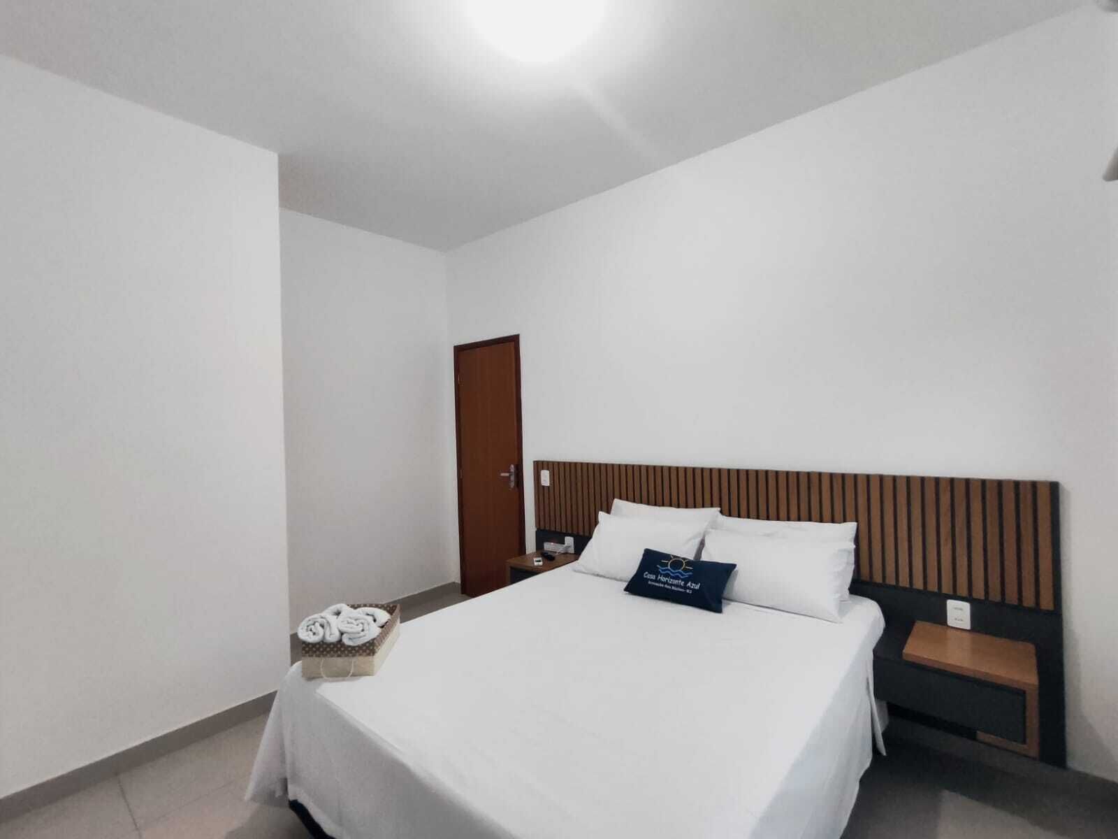 A hotel room with a bed, a wooden headboard, a nightstand, and a small table with towels.