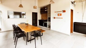 A spacious kitchen with a wooden dining table and chairs, a brick wall, and a hanging light fixture.