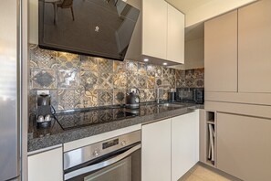 A modern kitchen with a patterned backsplash, stainless steel appliances, and a built-in oven.