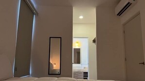 A hotel room with a bed, a mirror, and an air conditioning unit. - Cozy 2-bedroom condo with rooftop terrace w/arch view in Cabo San Lucas (cabo san lucas)