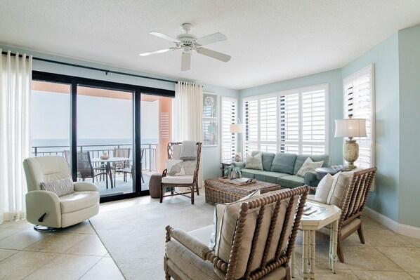 Ein geräumiges Wohnzimmer mit Balkon, Deckenventilator und Meerblick.