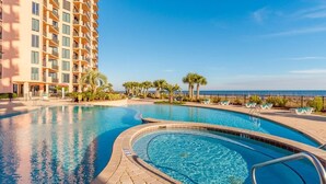 A hotel with a large outdoor swimming pool, palm trees, and a view of the ocean. - Sea Chase Resort, Gulf Front Condo 3 bd/3 ba, Fitness Room, 5 pools, 4 Hot Tubs (Orange Beach)