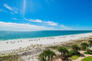 Ein Strand mit blauem Himmel, sandigem Ufer und einigen Sonnenschirmen.