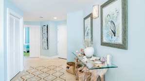A hallway with a glass console table, framed artwork, and a patterned rug. - Sea Chase Resort, Gulf Front Condo 3 bd/3 ba, Fitness Room, 5 pools, 4 Hot Tubs (Orange Beach)