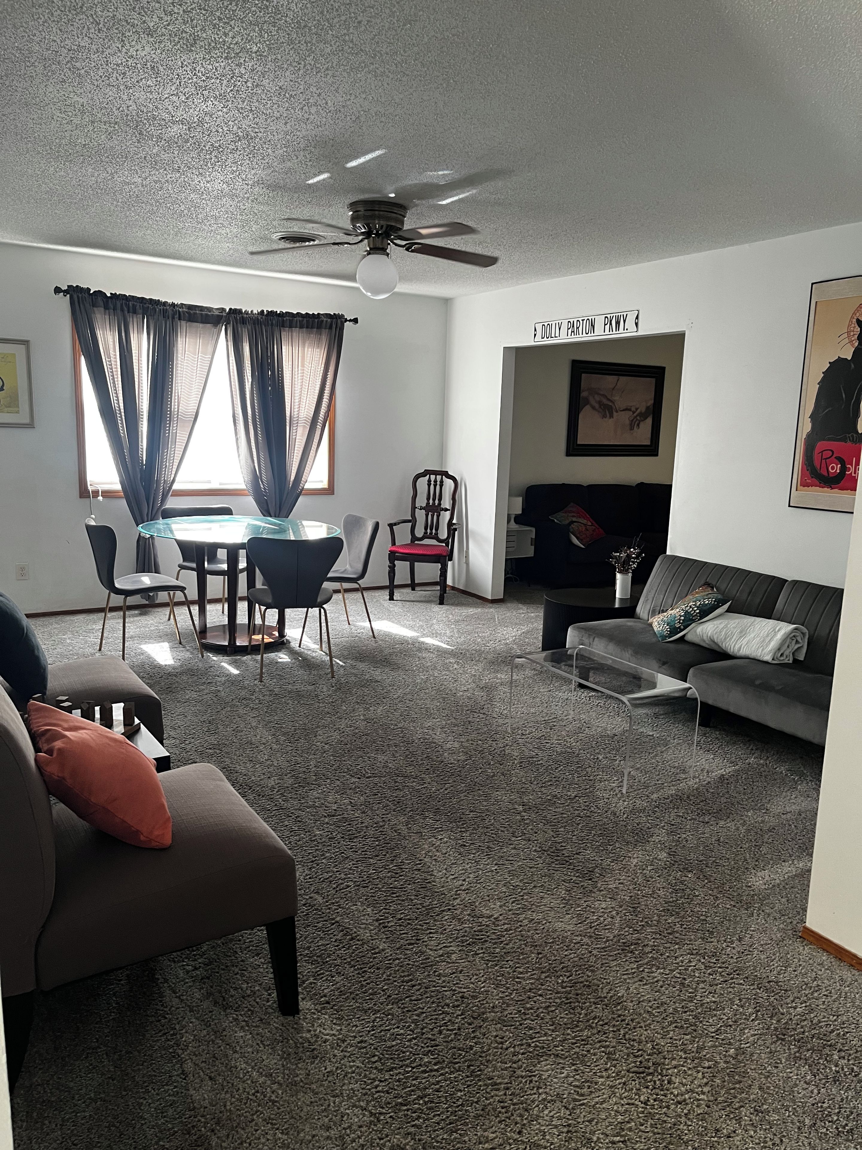 A living room with a ceiling fan, a dining table with chairs, a sofa, and a couch.