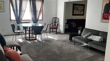 A living room with a ceiling fan, a dining table with chairs, a sofa, and a couch.