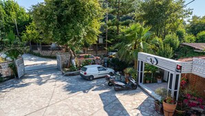 A paved driveway leading to a gated entrance with a white car and a scooter parked nearby. - Apartment 'Alex Bar 4' with Sea View, Wi-Fi and Air Conditioning (Parga)