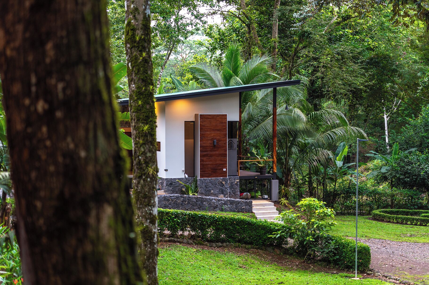 A modern house with a stone facade, a wooden door, and a small porch.