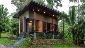 Een modern huis met balkon, omgeven door weelderig groen.