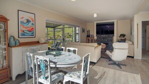 A dining area with a round table and chairs, a sofa, a fireplace, and a view of the outdoors.