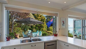 A modern kitchen with a large window, stainless steel appliances, and a view of the outdoors.