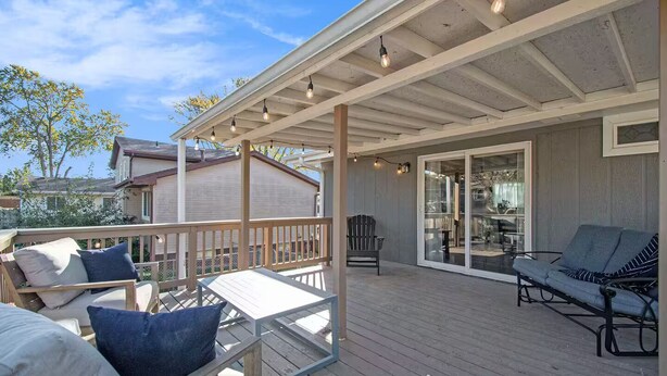 A covered patio with wooden flooring, a wooden deck, and a glass door leading to an interior space. - Modern 4BR Gretna NE, Garage, Fenced Yard, W/D, Pet-Friendly, Near Outlets (Gretna)
