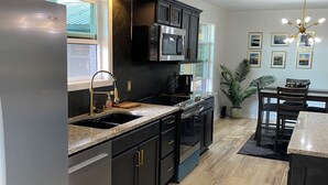 Una cucina moderna con mobili scuri, elettrodomestici in acciaio inossidabile e un piano di lavoro in granito.